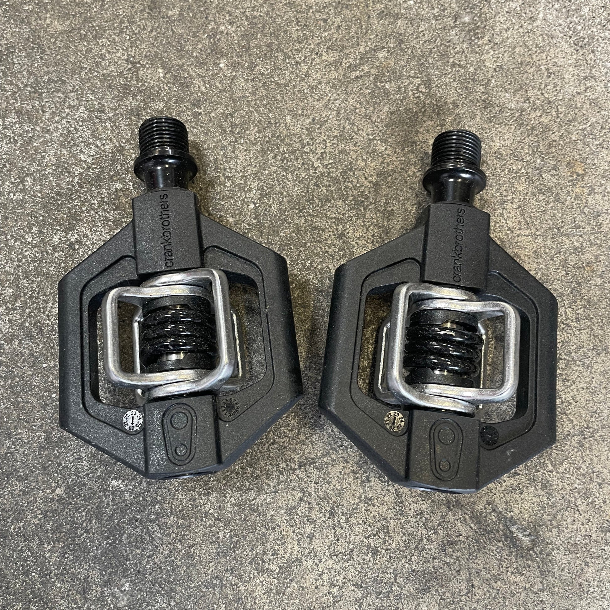 Two black bicycle pedals on a gray surface