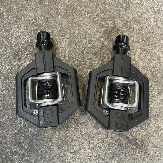 Two black bicycle pedals on a gray surface