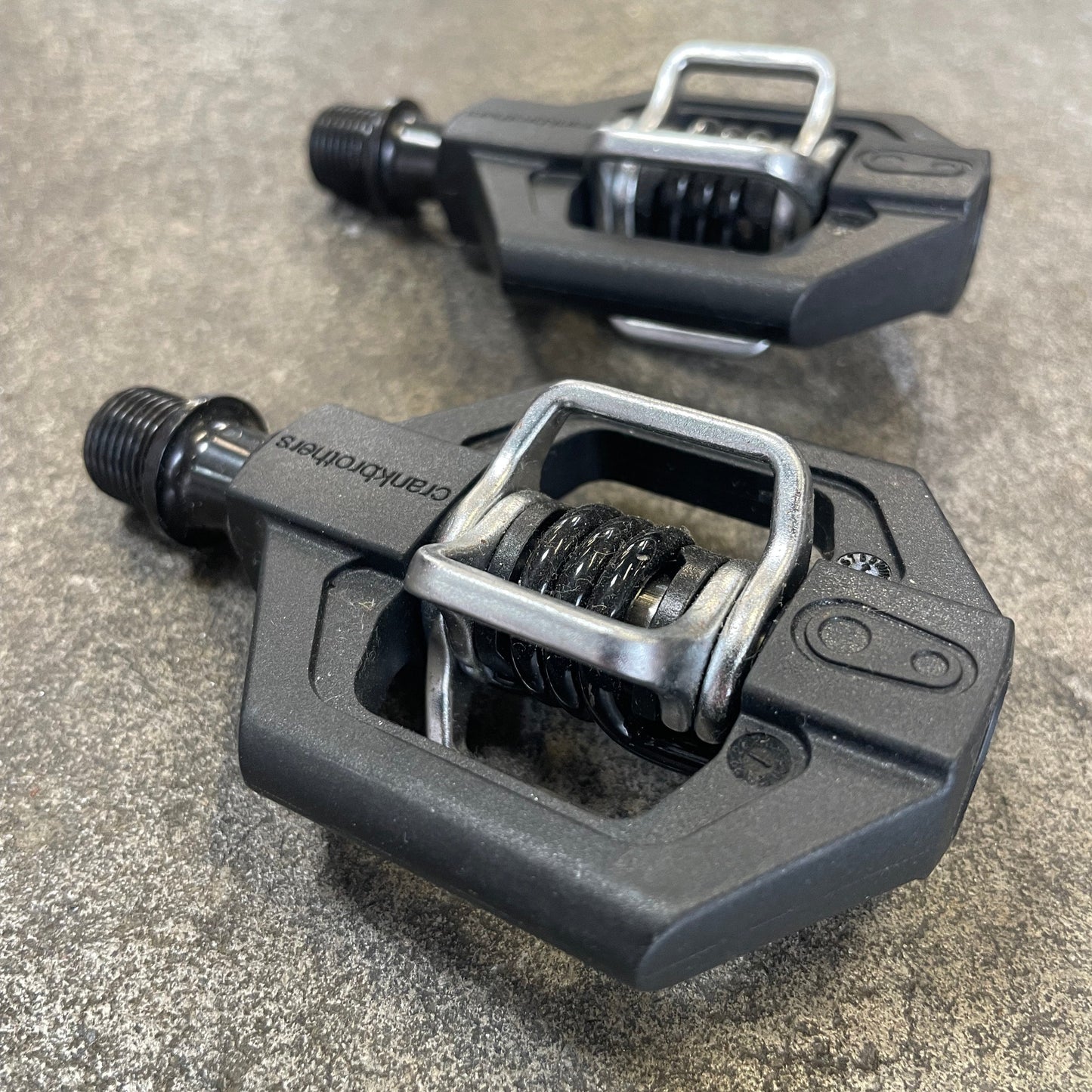 Pair of black bicycle pedals on a concrete surface