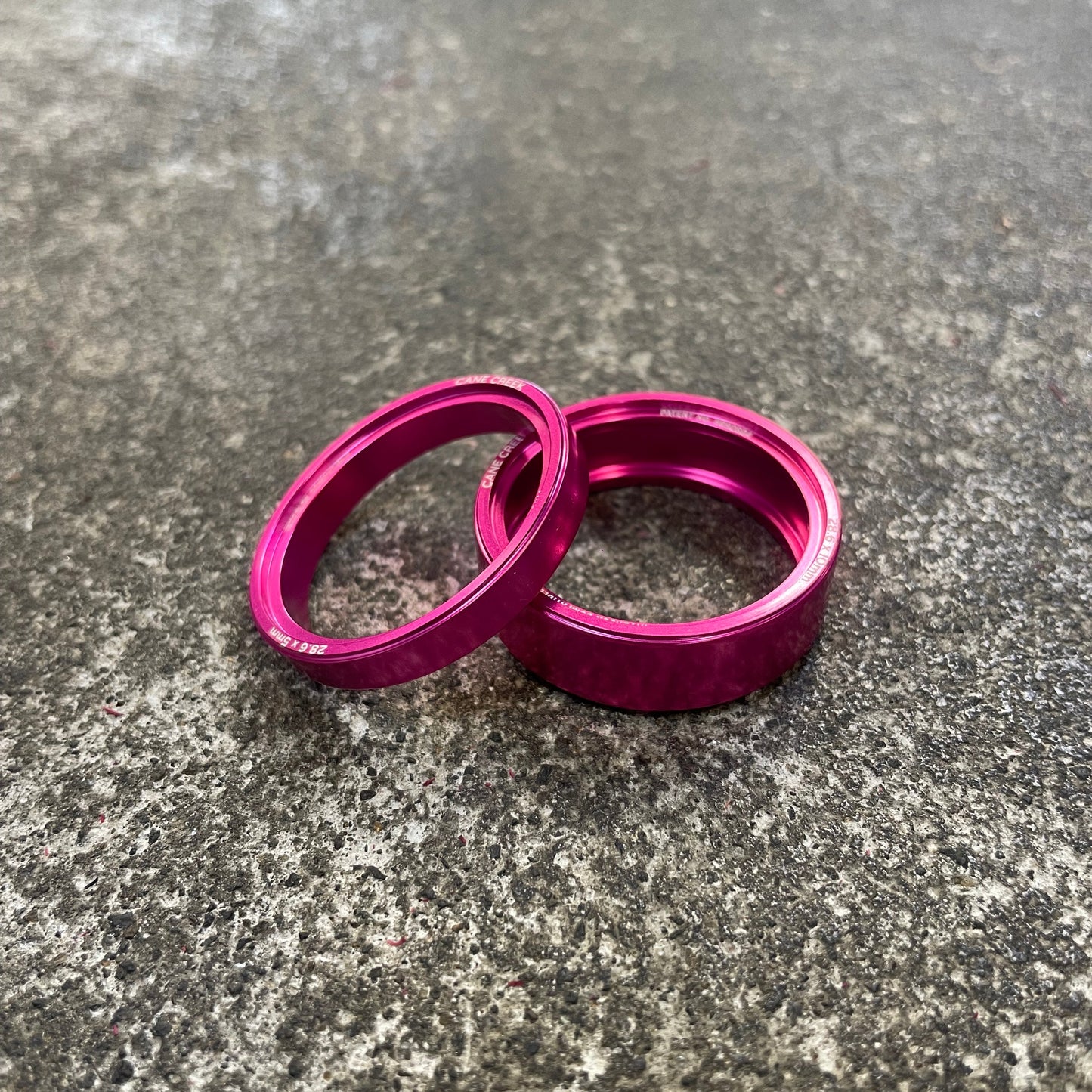 Two pink metal rings on a textured gray surface