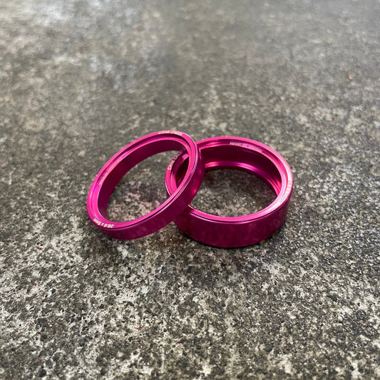 Two pink metal rings on a textured gray surface