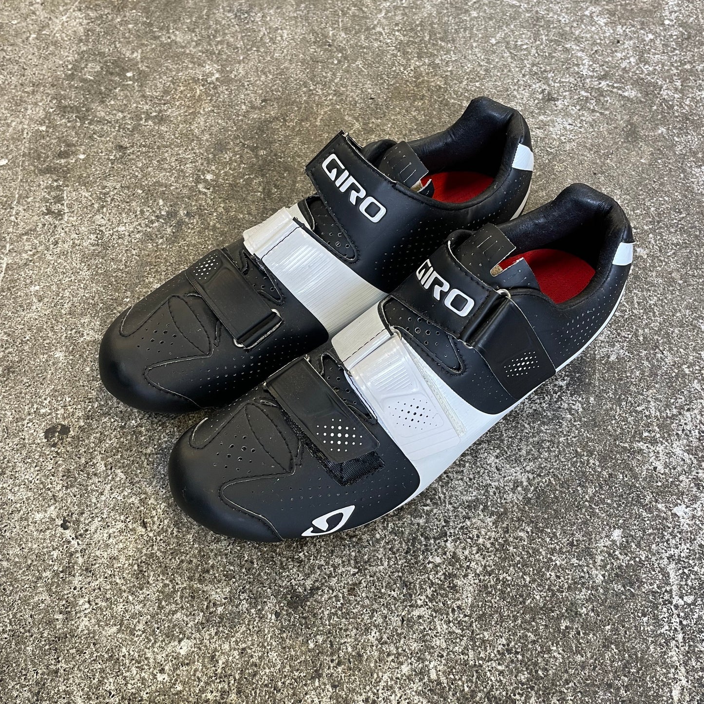 Pair of black and white cycling shoes on a concrete surface
