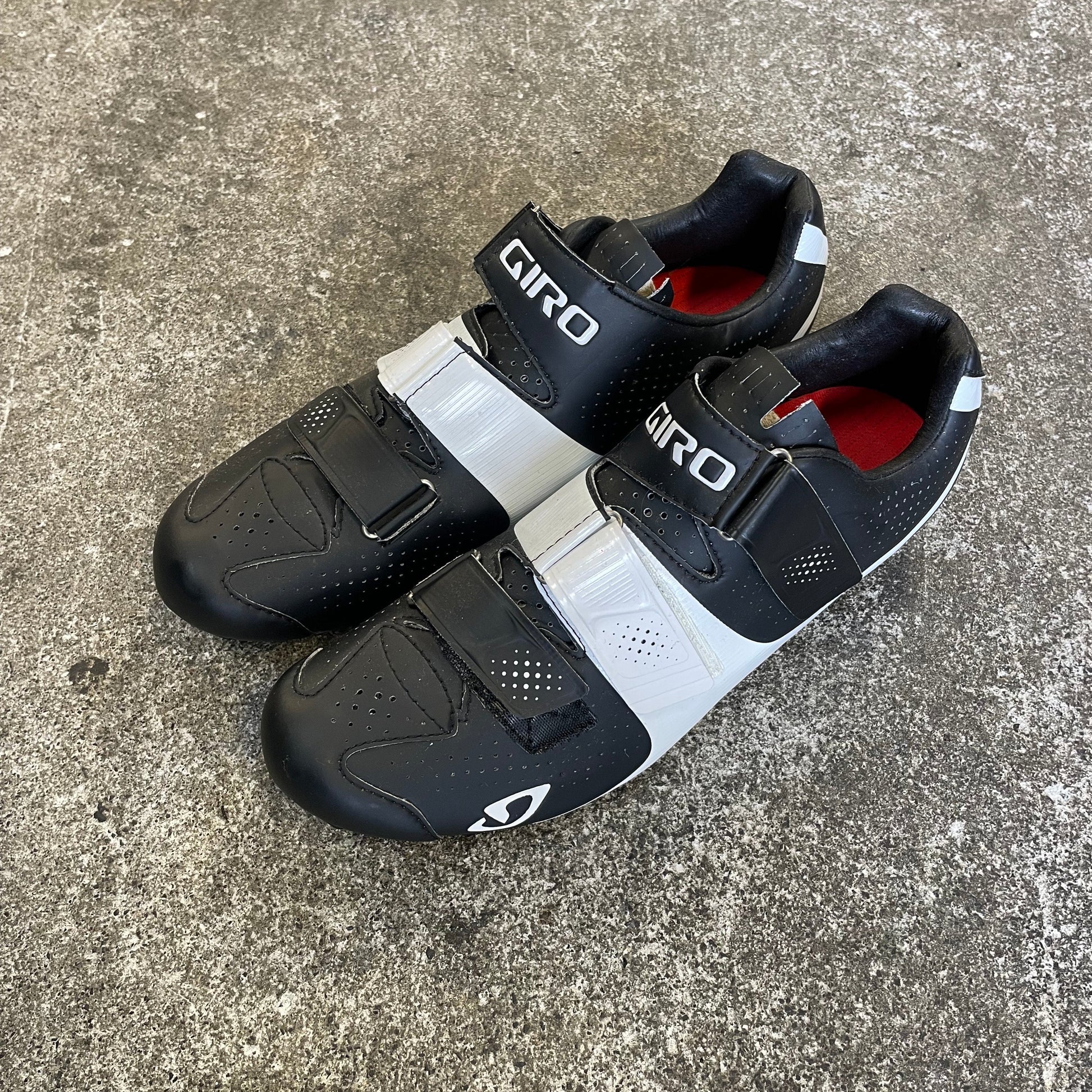 Pair of black and white cycling shoes on a concrete surface