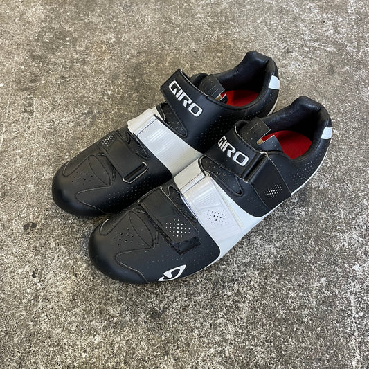 Pair of black and white cycling shoes on a concrete surface